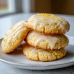 A stack of three delicious, glazed lemon cookies topped with bright yellow lemon zest.