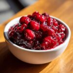 Close-up of chunky, glossy homemade cranberry sauce served in a small white bowl.