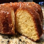 Close-up of a moist slice cut from a Bacardi Rum Cake, showing the yellow crumb and rich rum glaze dripping down.