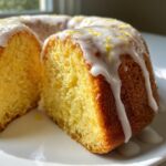 Close-up of a moist slice of lemon pound cake topped with white glaze and lemon zest.