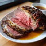 Close-up of a beautifully roasted prime rib, sliced to show a perfect medium-rare center and seasoned crust.