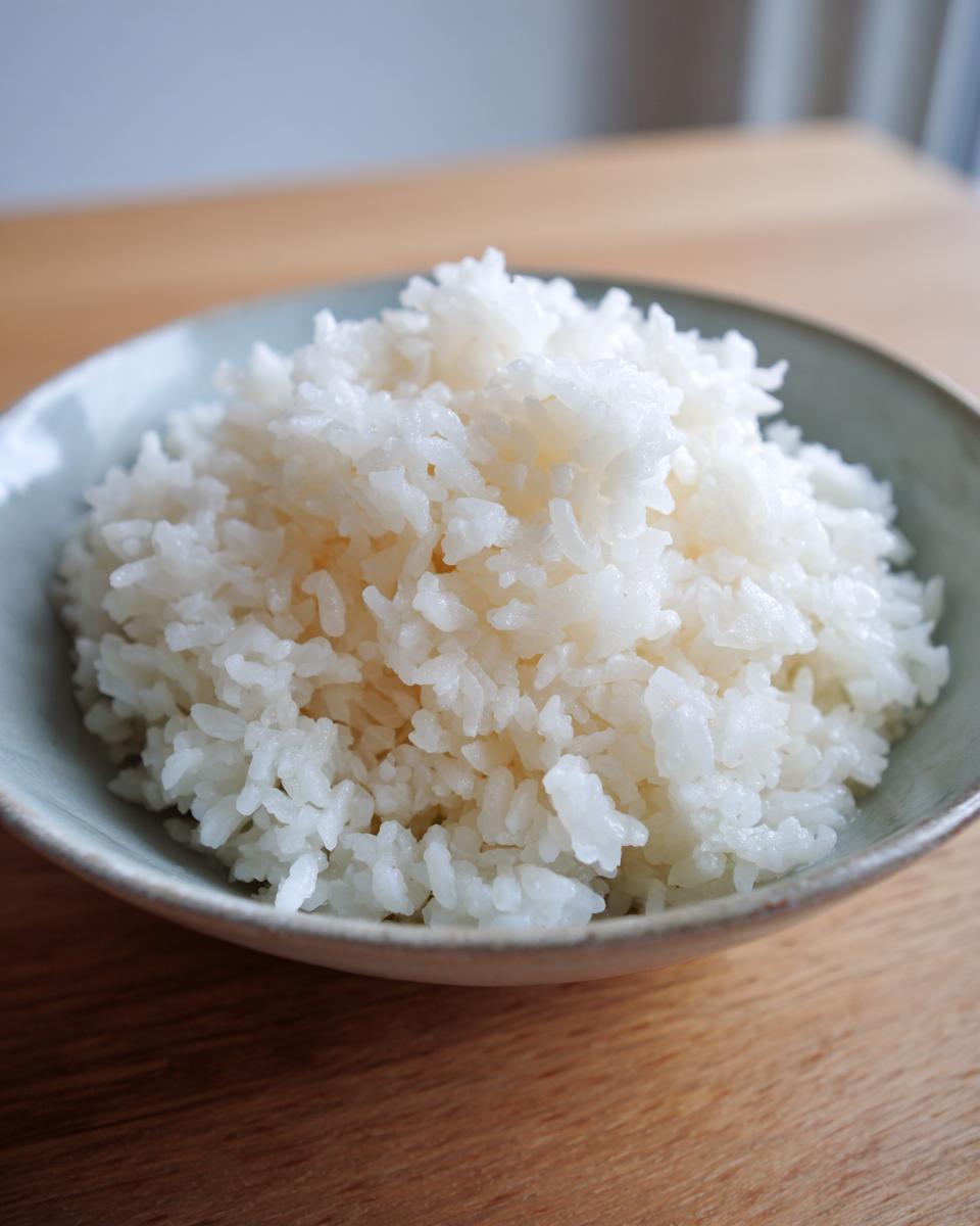 Close-up of perfectly cooked, fluffy white sushi rice served in a light blue ceramic bowl.