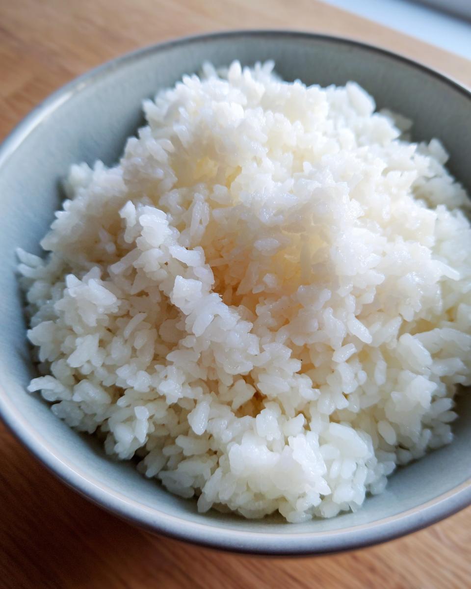 Close-up of fluffy, perfectly cooked sushi rice in a light blue ceramic bowl.