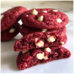 Close-up of soft red velvet cake mix cookies stacked, showing a cross-section revealing gooey white chocolate chips.