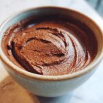Close-up of rich, dark chocolate pudding swirled in a small ceramic bowl.
