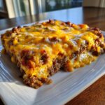 A hearty slice of meatloaf casserole topped generously with melted cheddar and white cheese.