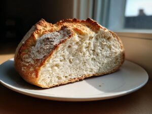 A close-up of a freshly baked loaf of soda bread, cut open to show the soft, airy crumb and golden crust.