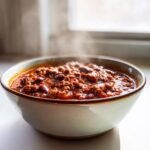 A steaming bowl filled with rich, hearty chili featuring ground meat and kidney beans, showcasing the best chili recipe.