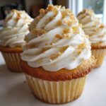 A close-up of delicious banana pudding cupcakes topped with swirled white frosting and crushed wafer crumbs.