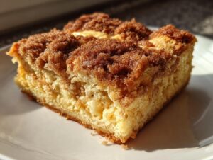 A close-up of a square slice of baked french toast topped with thick, sugary cinnamon streusel.