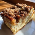 Close-up of a square slice of baked french toast topped with a thick, glistening cinnamon streusel.