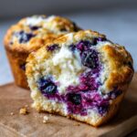 Close-up of a blueberry cream cheese muffins cut in half, showing a rich cream cheese center and burst blueberries.