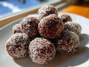 A close-up stack of rich, dark bourbon balls generously coated in white granulated sugar.