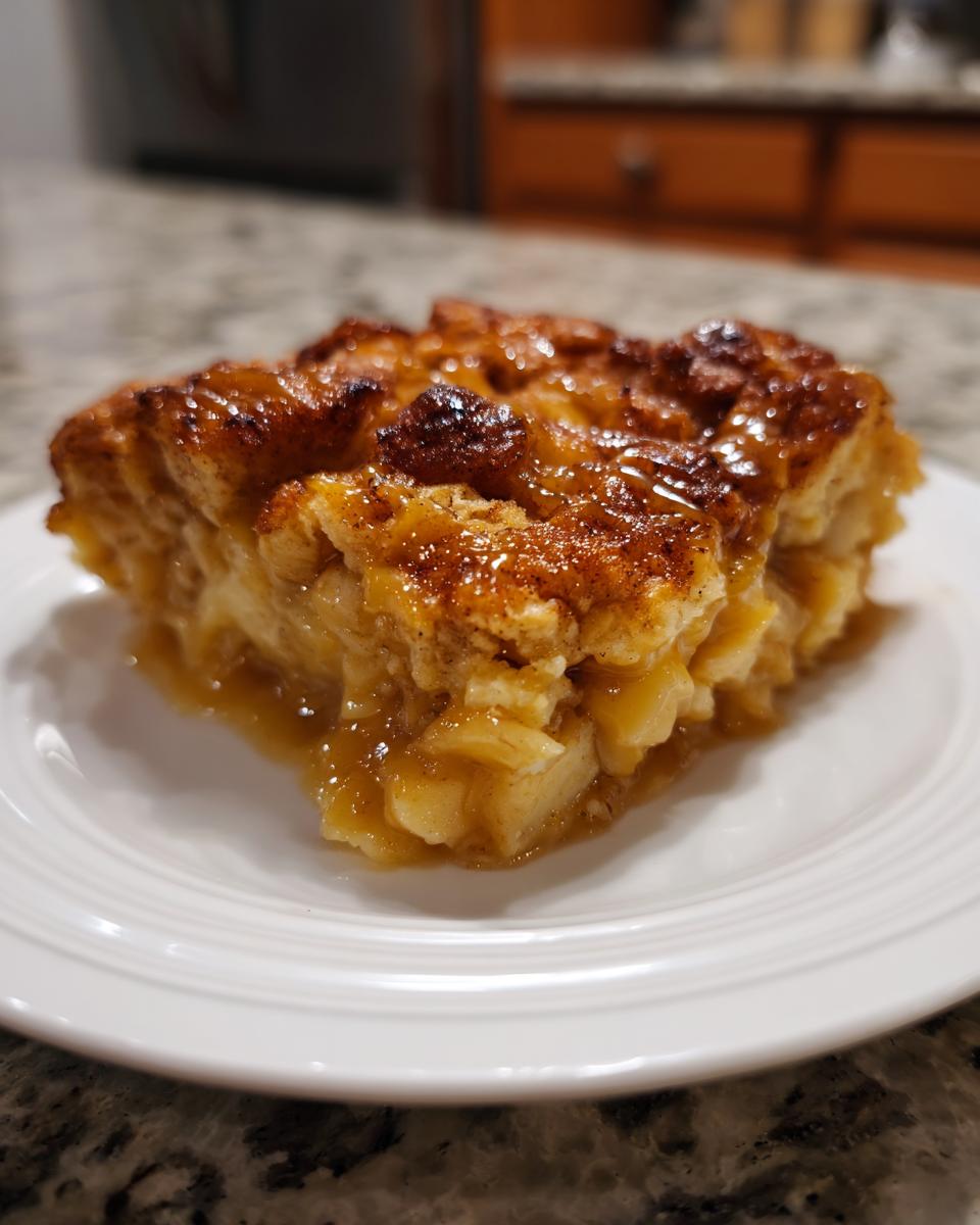 A close-up of a square slice of warm caramel apple dump cake, glistening with caramel sauce.
