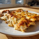 Close-up of two baked shrimp enchiladas covered in melted, browned cheese, served on a white plate.