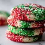 A close-up stack of four soft Christmas sprinkle sugar cookies covered in festive red, green, and white nonpareils.