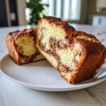 Two thick slices of cream cheese banana bread showing a rich cinnamon swirl filling and crumb topping.
