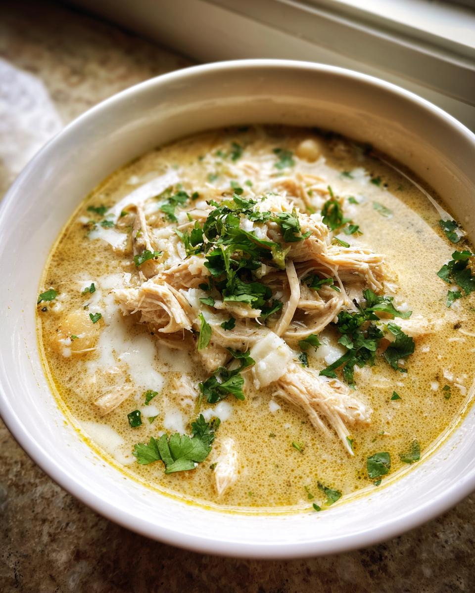 A close-up of a creamy white chicken chili recipe, topped with shredded chicken and fresh cilantro.