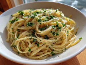 Close-up of creamy parmesan pasta tossed with fresh parsley and grated cheese in a white bowl.