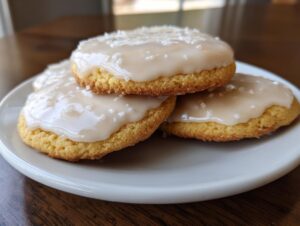 A stack of three soft sugar cookies topped with smooth, slightly off-white sugar cookie icing and coarse salt crystals.