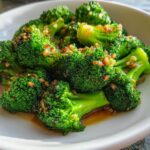 Vibrant green, perfectly steamed broccoli florets topped with browned garlic bits and a savory sauce.