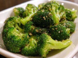 Close-up of bright green, perfectly steamed broccoli florets seasoned with minced garlic.