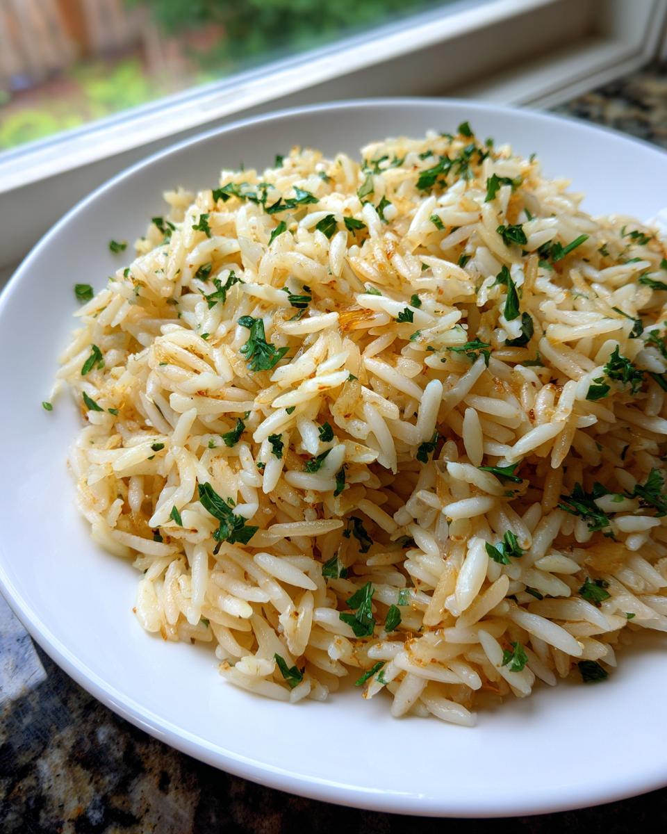 A close-up of fluffy rice pilaf served on a white plate, topped with chopped fresh parsley.