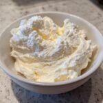 Close-up of fluffy, white snow ice cream served in a small white bowl on a speckled counter.