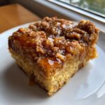 Close-up of a square slice of baked french toast casserole topped with a sticky, brown sugar crumble and syrup.