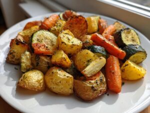 A close-up of perfectly roasted potatoes, carrots, and zucchini seasoned with herbs, representing Garlic Herb Roasted Veggies.