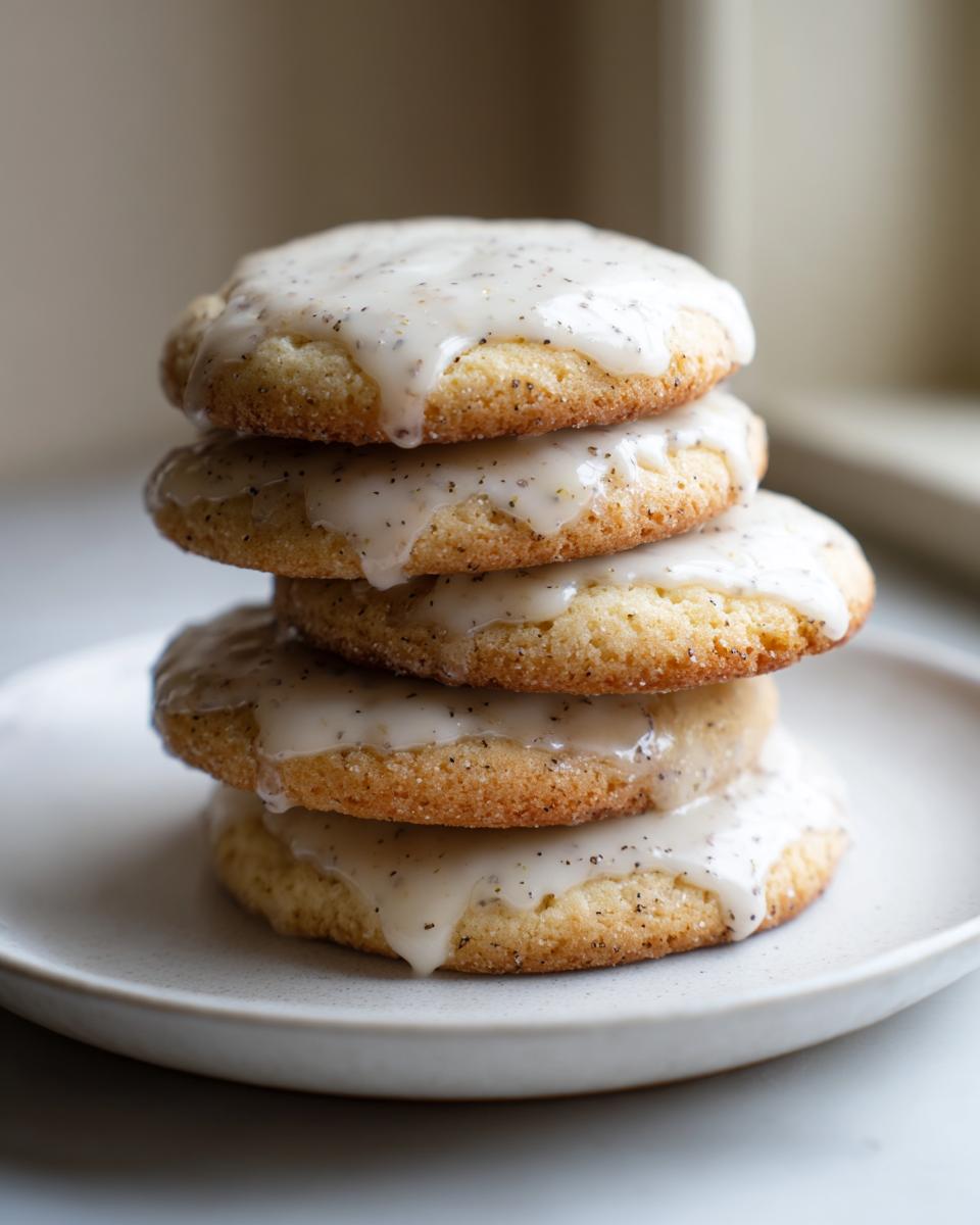 A stack of four soft, glazed earl grey cookies showing visible tea specks in the cookie and the dripping icing.