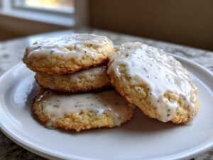 A stack of four golden brown earl grey cookies topped with a thick, speckled vanilla glaze.
