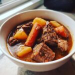 Close-up of tender beef chunks, carrots, and potatoes in a rich broth of crockpot beef stew.