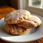 A stack of three soft maple brown sugar cookies topped with a sweet white glaze, sitting on a white plate.