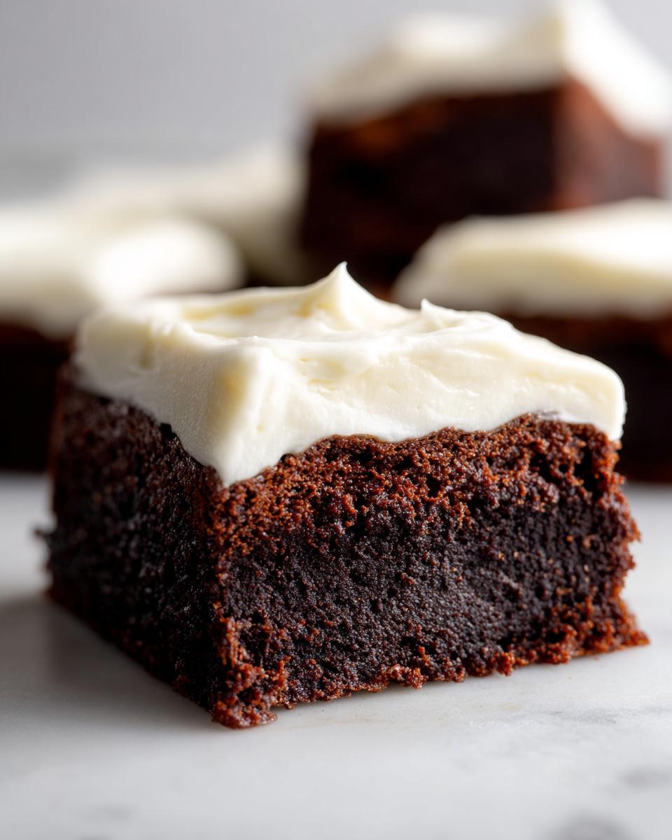 Close-up of a rich, dark gingerbread brownies square topped with thick, white cream cheese frosting.