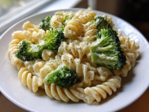A close-up of creamy one-pot broccoli pasta featuring fusilli noodles and bright green broccoli florets, seasoned with pepper.