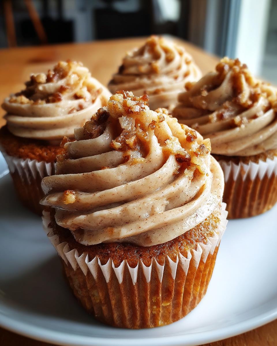 A close-up of delicious pecan pie cupcakes featuring swirled brown sugar frosting topped with chopped pecans.