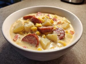 Close-up of a creamy bowl of potato and sausage chowder topped with cracked black pepper.