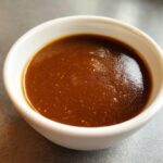 Close-up of rich, dark homemade brown gravy served in a small white ramekin.