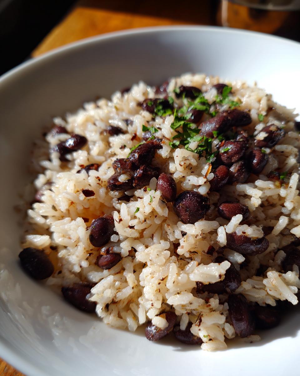 Close-up of fluffy white rice mixed with dark black beans and topped with fresh parsley, a serving of black beans and rice.