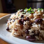 A close-up, appetizing shot of a serving of savory black beans and rice, topped with fresh green herbs.