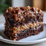 Close-up of a moist slice of german chocolate cake layered with coconut-pecan frosting.