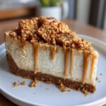 A close-up shot of a perfect slice of biscoff cheesecake topped with caramel sauce and crushed cookies.