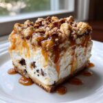 A decadent slice of turtle cheesecake topped with pecans, caramel, and a creamy filling with chocolate pieces.