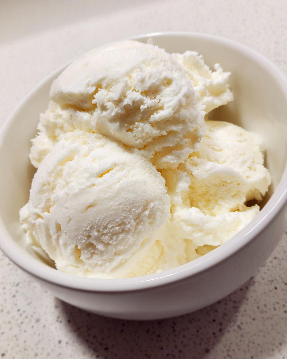 Close-up of three scoops of white, fluffy snow ice cream served in a small white bowl.