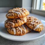 A stack of four moist coffee cake cookies topped with cinnamon streusel and drizzled with white icing.