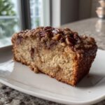 A close-up of a moist slice of sweet Alabama pecan bread topped with a crunchy pecan streusel.