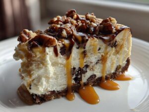 A decadent slice of turtle cheesecake topped with pecans, chocolate, and dripping caramel sauce.