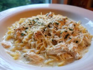 A close-up of creamy chicken parmesan soup served over rotini pasta, topped with shredded Parmesan and parsley.