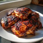 Close-up of several pieces of deeply caramelized Hawaiian Huli Huli Chicken on a white plate.